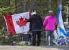 A couple place a flag at a memorial in Portapique, N.S. on Wednesday, April 22, 2021. RCMP say at least 22 people are dead after a man who at one point wore a police uniform and drove a mock-up cruiser, went on a murder rampage in Portapique and several other Nova Scotia communities. THE CANADIAN PRESS/Andrew Vaughan