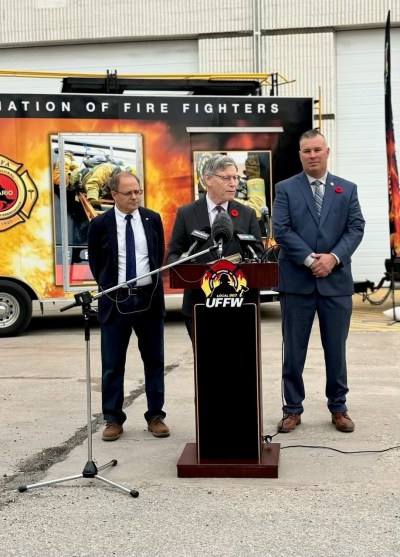 Submitted 

Winnipeg South MP Terry Duguid talks at the podium during the announcement of the investment of $12 million into cancer awareness and prevention for firefighters on Nov. 1 at the Winnipeg Fire Paramedic Training Academy, Stores, and Mechanical Services. He is flanked by Winnipeg North MP Kevin Lamoureux and United Firefighters of Winnipeg President Tom Bilous.